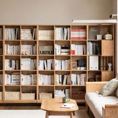 a living room filled with lots of wooden bookshelves next to a white couch