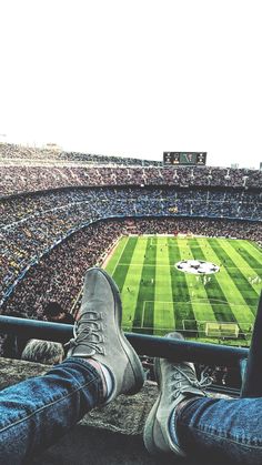 a person's feet are sitting on the edge of a railing at a football stadium