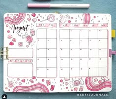 a planner with pink and white doodles on it next to a marker, pen and paper