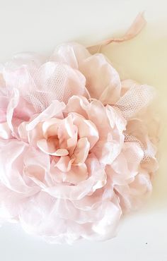 a large pink flower on top of a white surface with netting around the petals and attached to a headband