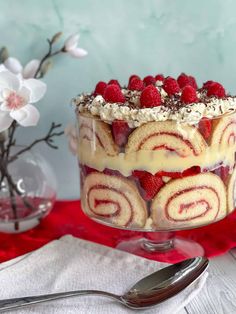 a red and white dessert with raspberries on top is sitting on a table