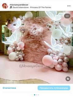 a pink and white backdrop with balloons on the floor, flowers in the center and butterflies at the top