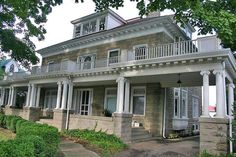 an old brick house with white columns and balconies on the second story porch