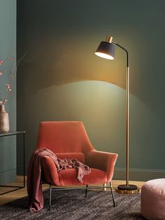 a living room with an orange chair and a lamp on the floor next to it