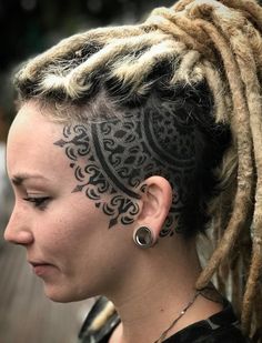 a woman with dreadlocks has a tattoo on her head