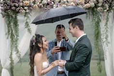 a bride and groom standing under an umbrella