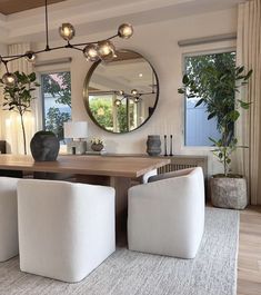 a living room with two chairs and a table in front of a large round mirror