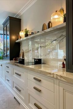 a kitchen with white cabinets and marble counter tops, along with glass doors leading to an outside patio