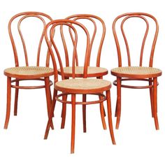 four wooden chairs with wicker seats on them