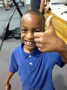 a young boy giving the thumbs up sign