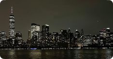 the city skyline is lit up at night with lights reflecting in the water and skyscrapers