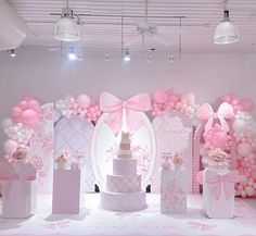 a pink and white birthday party setup with balloons, cake, gift boxes and decorations