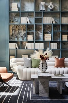 a living room filled with white furniture and lots of bookshelves behind the couch