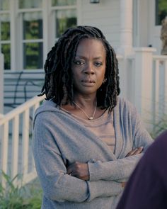 a woman with dreadlocks standing in front of a house