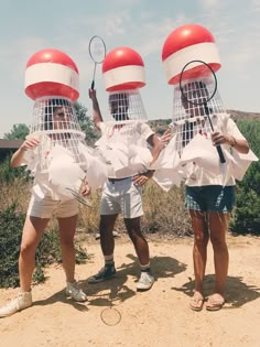 three people wearing identical hats with tennis rackets on their heads and holding tennis racquets in each other's hands