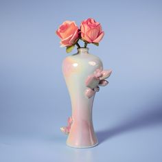 there is a vase with two pink roses in it on the table and blue background