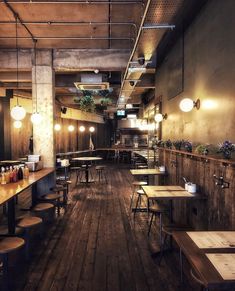 an empty restaurant with tables and stools on the floor, lights hanging from the ceiling