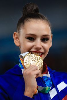 a woman holding up a gold medal in front of her face