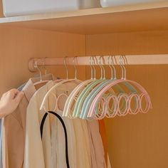 a person standing in front of a closet filled with clothes and handbags on hangers