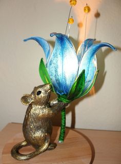 a glass mouse holding onto a blue flower