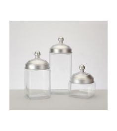 three glass jars with metal lids on a table