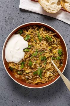 a bowl filled with beans, rice and sour cream on top of a gray table