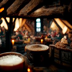 two mugs of beer sitting on top of a table next to some logs and candles