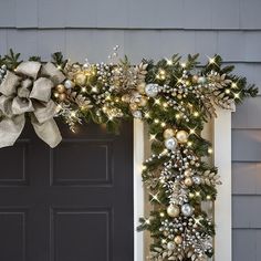 a christmas wreath on the front door with lights and ornaments hanging from it's sides