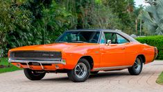 an orange muscle car parked on the side of a road