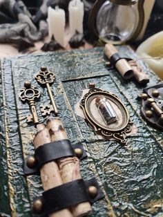 an assortment of antique keys and other items on a leather covered table top with candles in the background