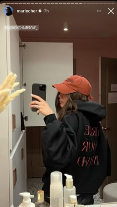 a woman taking a selfie in front of a mirror with her cell phone and other personal care products