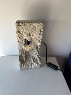 a light bulb sitting on top of a stone block next to a phone charger