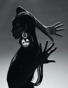 a black and white photo of a woman with her hands in the air, wearing large earrings