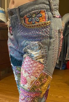 a woman's jeans with colorful patches and beads on the bottom, in front of a mirror