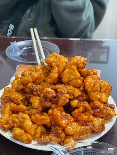 a plate full of fried food with chopsticks on the table next to it