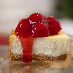 a piece of cheesecake with cherries on top and sauce drizzled over it