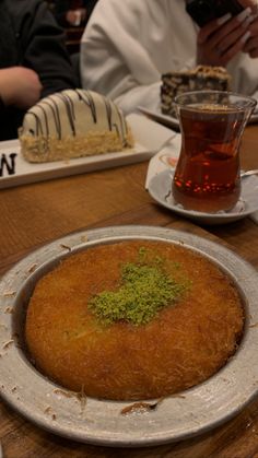 there is a large cake on the table with people in the background eating and drinking