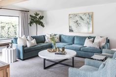 a living room filled with blue couches and pillows on top of a white table