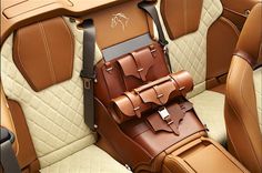 the inside of a car with brown leather seats and luggage on it's back