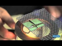 a close up of a person holding a piece of metal with green squares on it