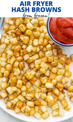 air fryer hash browns on a white plate with ketchup in the background