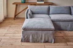 a blue couch sitting on top of a hard wood floor next to a wooden table