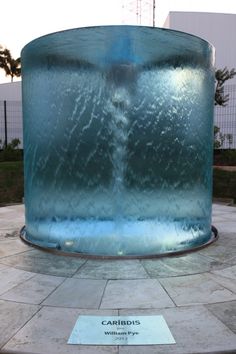 a large blue water tank sitting on top of a stone floor next to a building