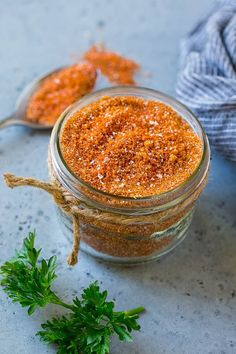 two spoons are next to a jar filled with seasoning