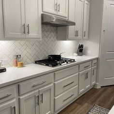 a kitchen with white cabinets and stainless steel stove top oven in the center of the room