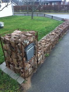 a pile of wood sitting on the side of a road in front of a fence