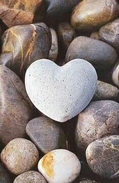 a heart - shaped rock with the words god is love on it surrounded by rocks