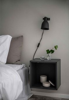 a nightstand with a lamp on top of it next to a bed