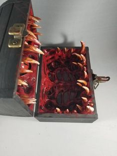 an open wooden box with red and gold designs on the inside, sitting on a white surface