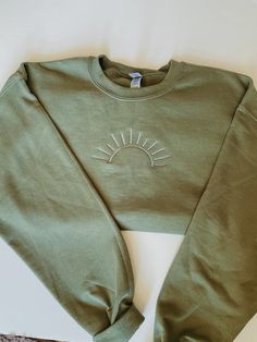 a green sweatshirt with the sun embroidered on it